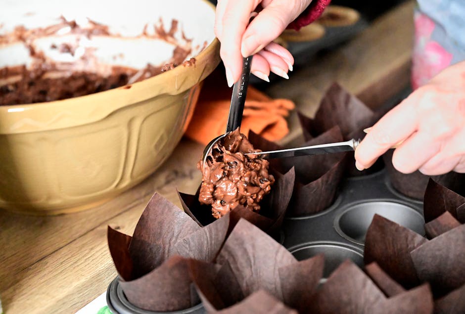 Pâte à muffins répartie à la cuillère dans des moules